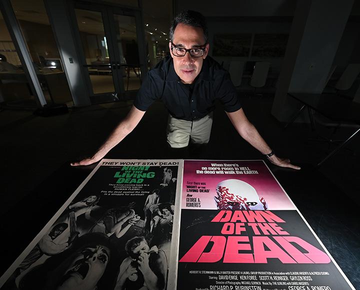 Adam Lowenstein behind two Romero movie posters