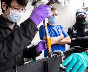 People gather around a machine that makes quantum computing parts