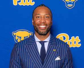 Fitzgerald stands in front of a Pitt branded background.