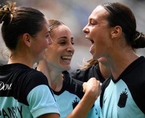 Three soccer players hug and cheer.