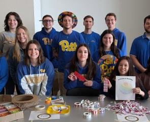 Students pose behind a table filled with art supplies.