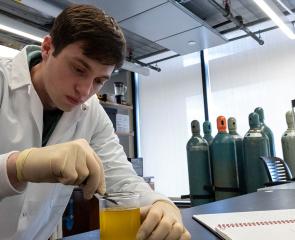 A student stirs a beaker in a lab.