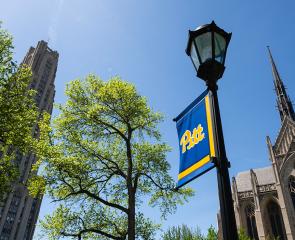 Cathedral of Learning and Heinz Chapel with a lamppost decorated with a Pitt banner