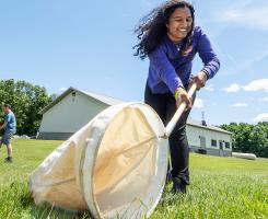 a smiling person with a big net in a field