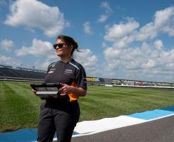 Gundlach holds a tablet while standing on a racetrack