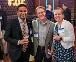 Three people hold drinks and smile.