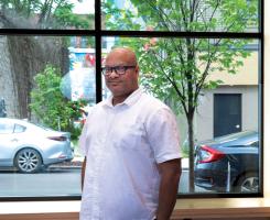Man with hands in pockets, standing in front of window.