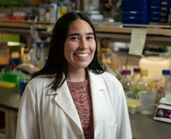 A woman wearing a lab coat smiles for camera.