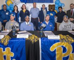 Pitt startup founders pose at a table with Pitt banners and Roc the panther