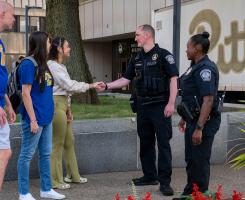 Public Safety police officer speak with and shake the hands of students.