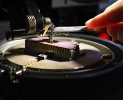 A hand uses a tool to adjust a small device