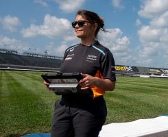 Kate Gundlach stands on a racing car track on a lightly cloudy day