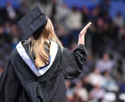 Student in graduation attire in front of a large audience