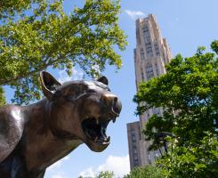 Summer image of the panther statue with the Cathedral of Learning behind it