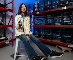 Woman sitting on stool posting for photo in lab holding medical device