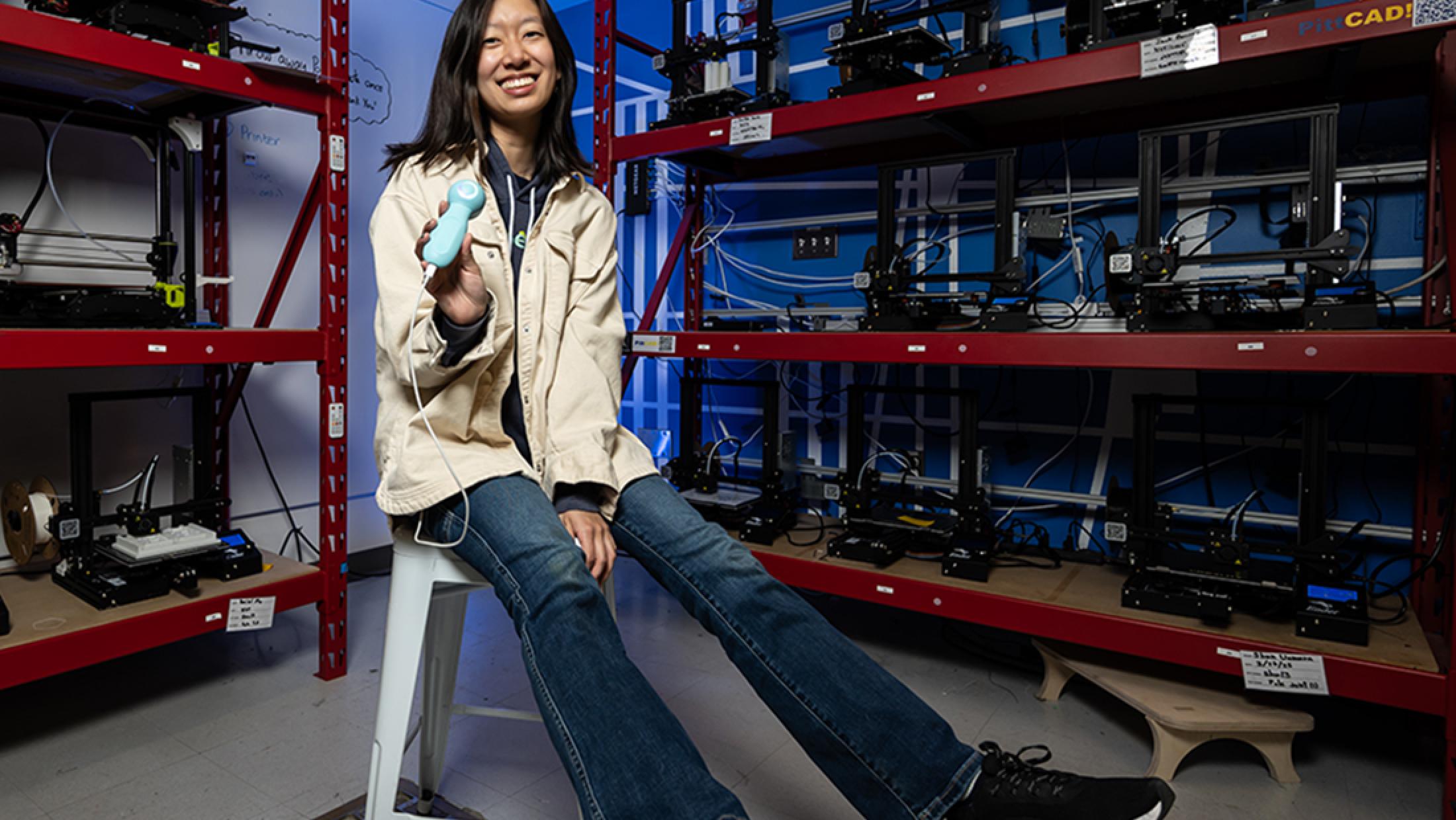 Woman sitting on stool posting for photo in lab holding medical device