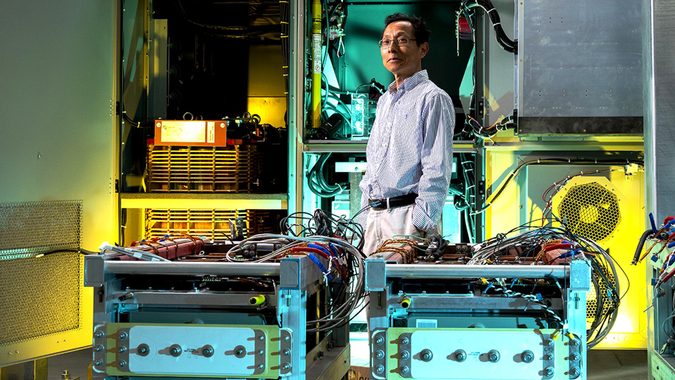 A researcher stands amid electrical engineering equipment in a well-appointed lab space.