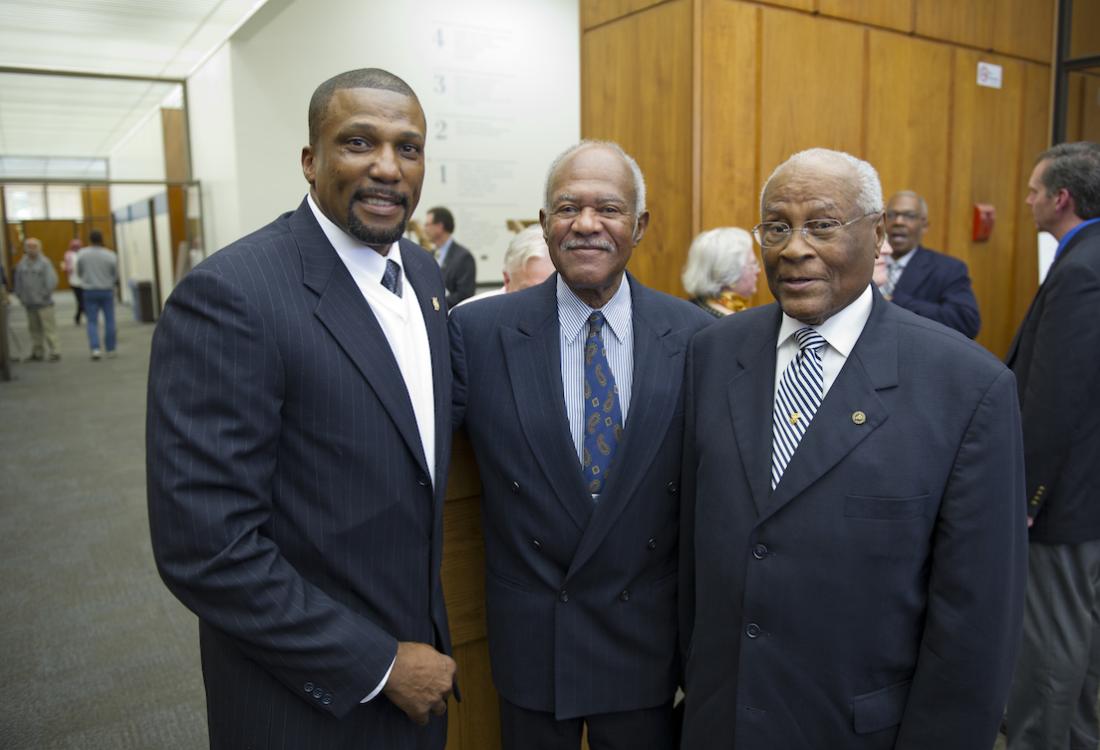 Three men in suits pose for a photo.