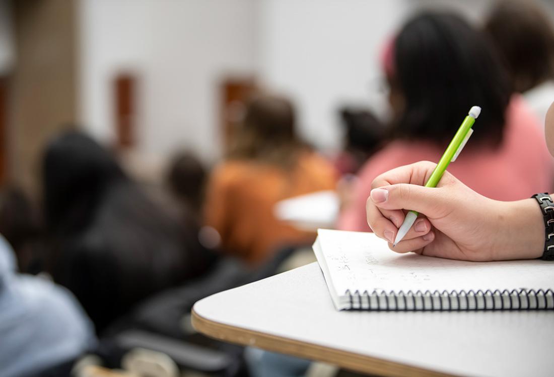 A hand writing in a notebook during class