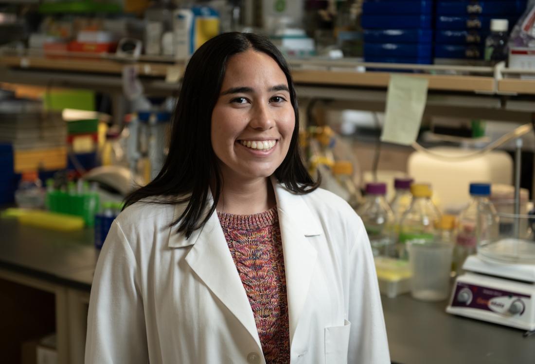 A woman wearing a lab coat smiles for camera.