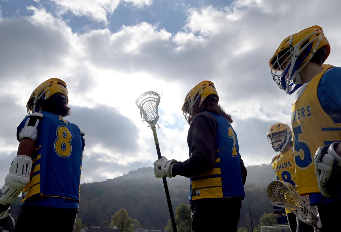 Lacrosse players silhouetted against clouds and mountains