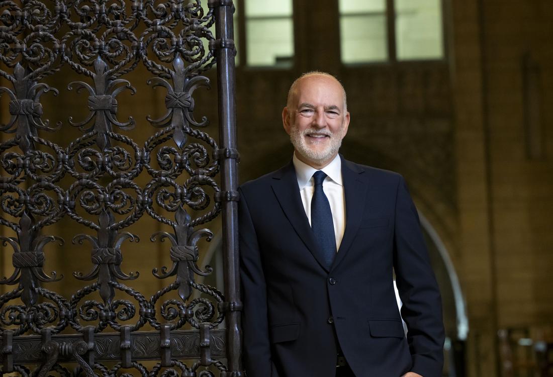 Man in suit smiling while standing near gate