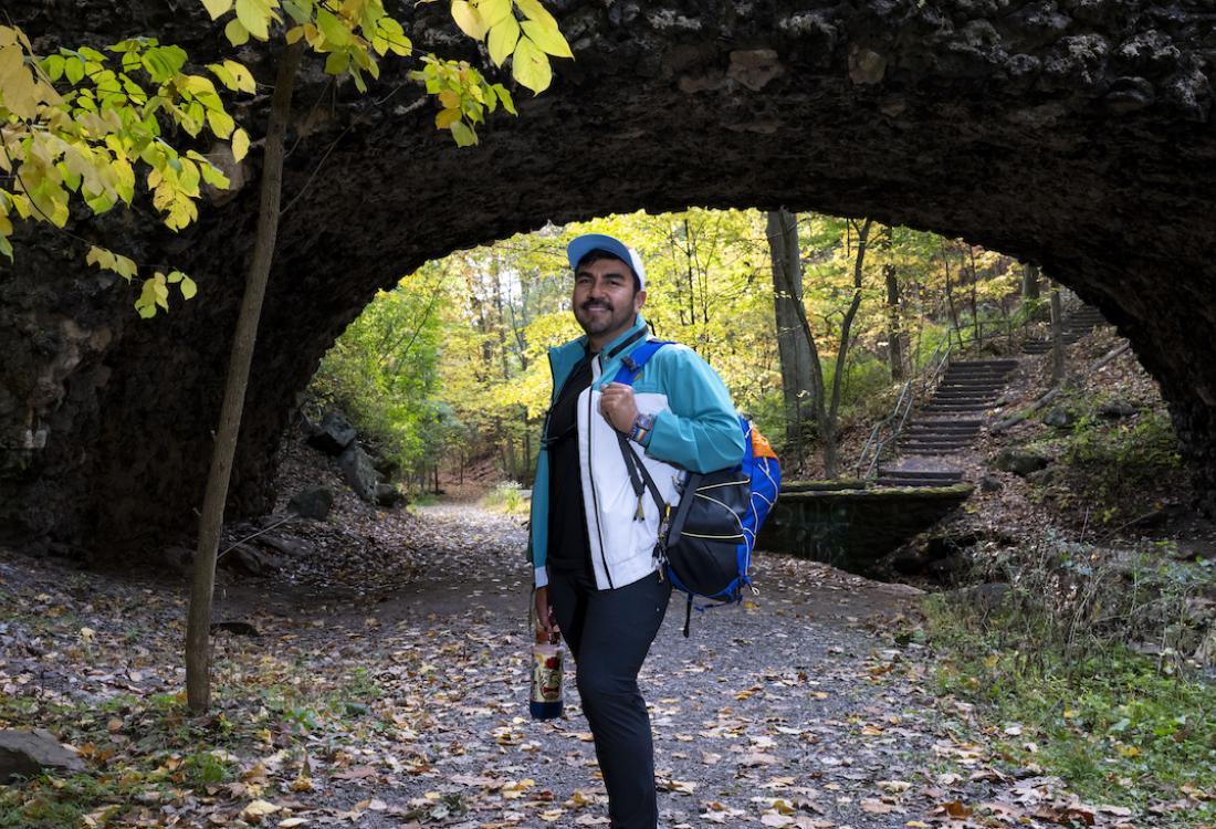 Man standing under a bridge along a wooded path