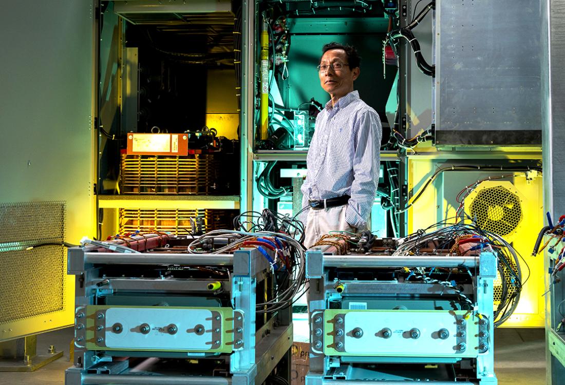 A researcher stands amid electrical engineering equipment in a well-appointed lab space.