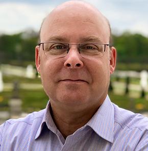 Headshot of a man standing outside on a sunny day