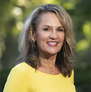 Headshot of woman wearing yellow with trees in background