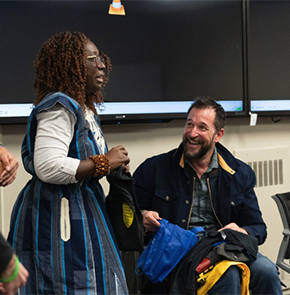 Owusu-Ansah peaks inside a classroom as a seated Wyle smiles