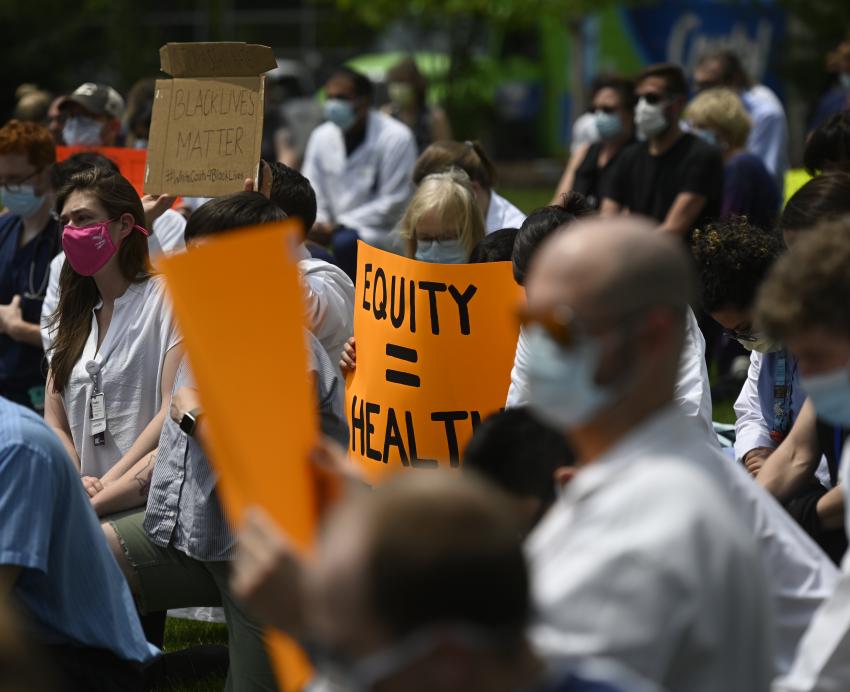 People in masks holding up signs, one saying "Equity = Health"