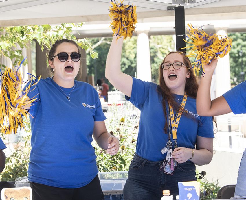 Four Pitt students wearing matching blue Pitt shirts cheering