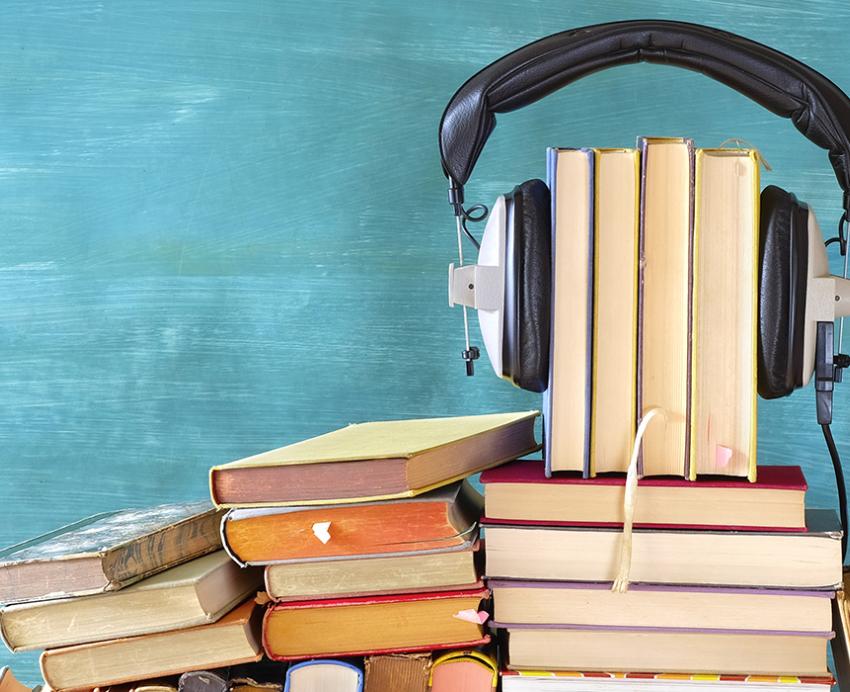 A pile of books, four of which are held together with a headset