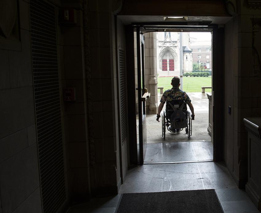 Student with wheelchair going through a doorway