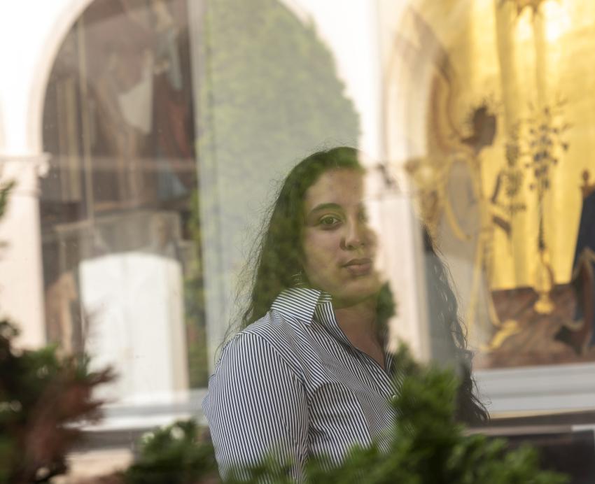 Stephanie Jimenez wearing striped shirt, artwork in the background