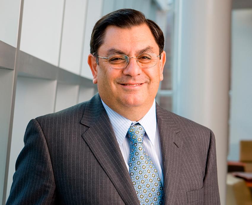Arjang Assad wearing grey suit and glasses, smiling