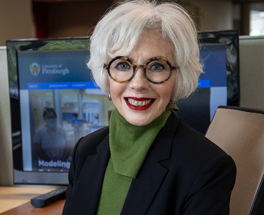 Patricia Kroboth wearing green shirt with black jacket, smiling in office