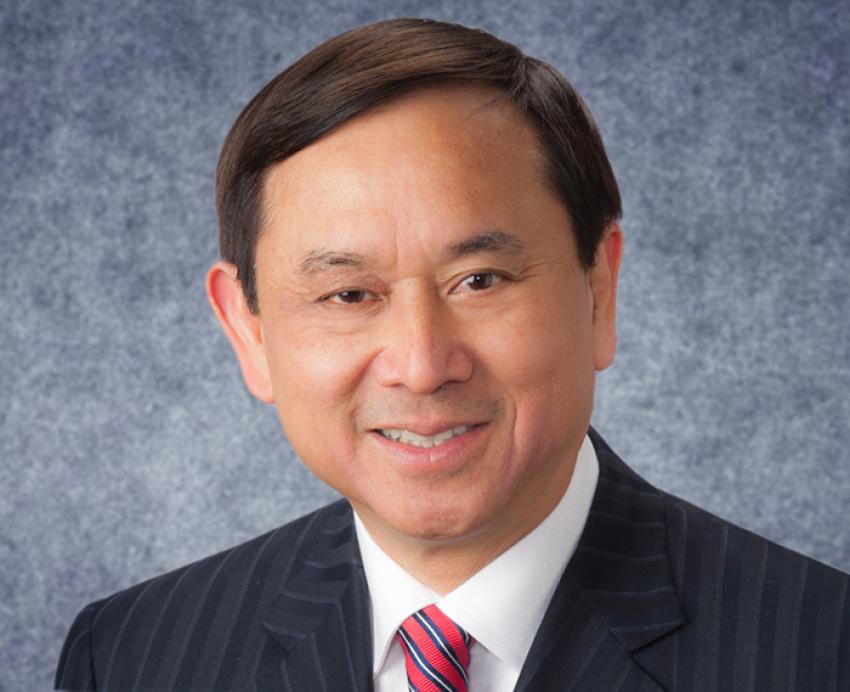 Freddie Fu smiling in black suit with red tie