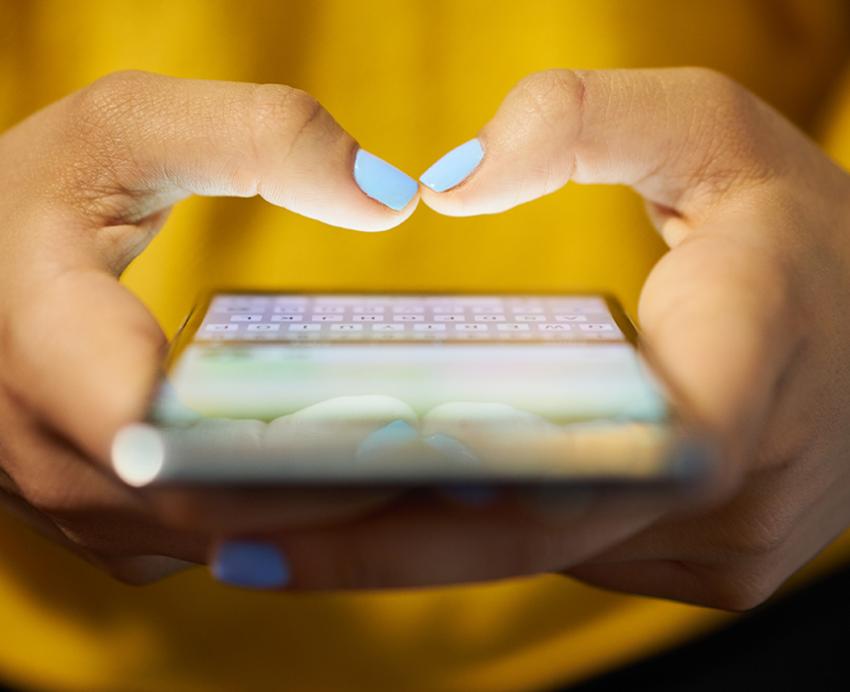 Person with yellow shirt typing on cellphone