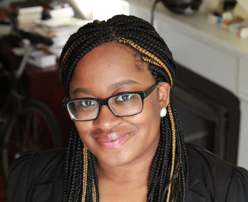 Keisha Blain smiling, wearing glasses with earrings and black shirt