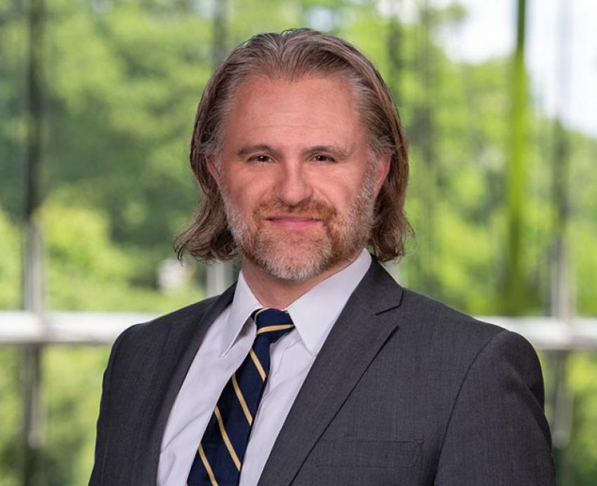 Charles Kotuby wearing grey suit with trees in background