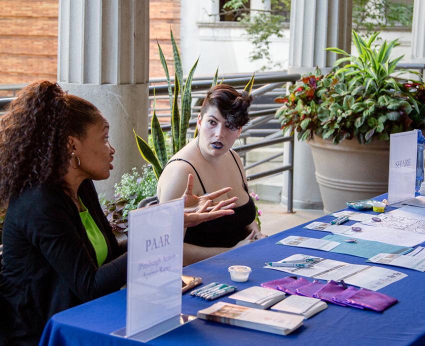 Two people working at an information table discussing PAAR