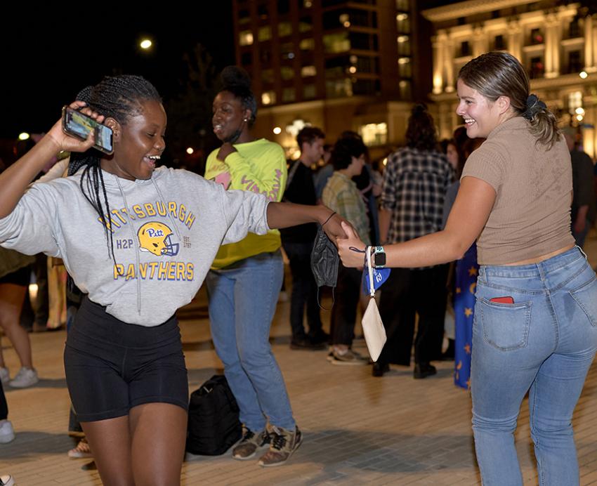 Two girls dancing, holding hands in a crowd
