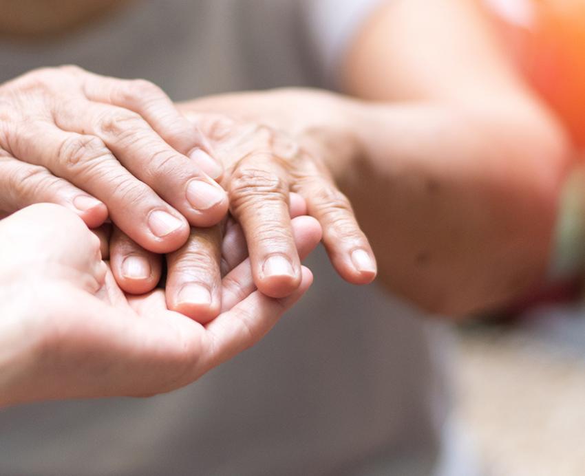 Elderly hands being held by another hand