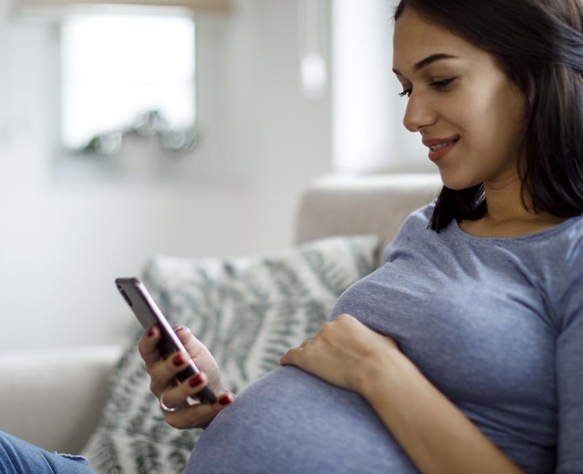 Pregnant woman using cellphone on the couch