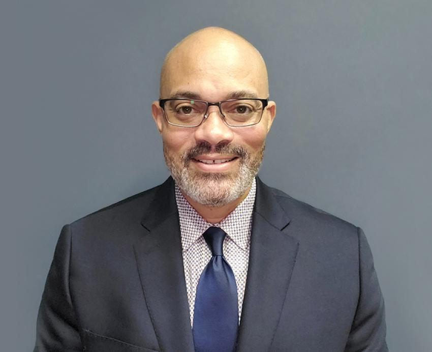 James Gallaher smiling with dark grey suit and navy blue tie
