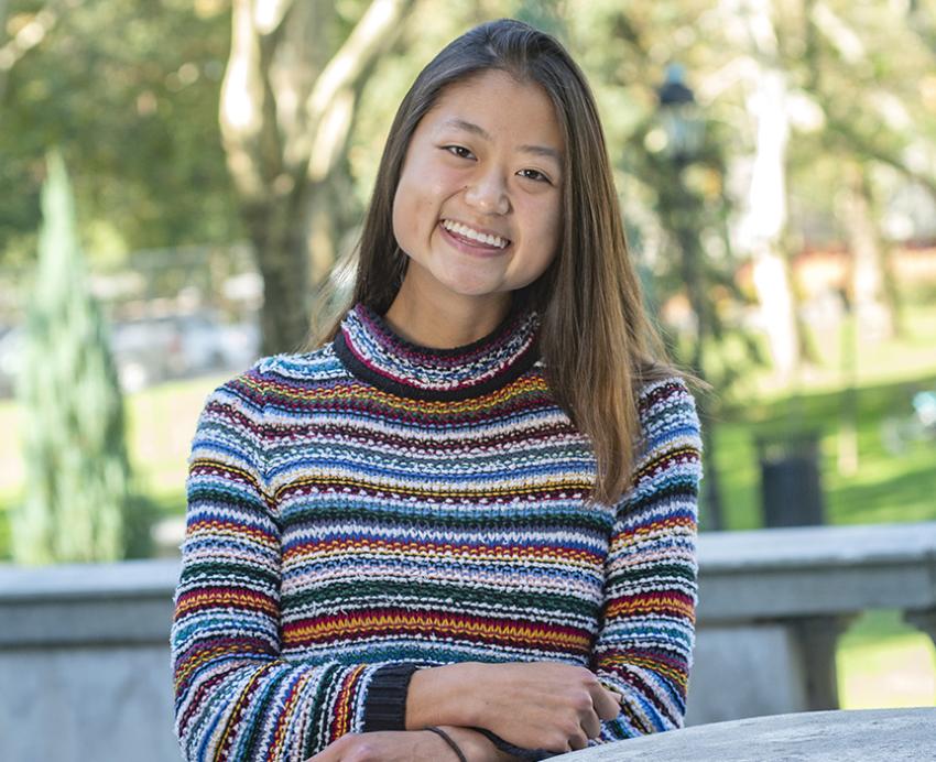 Yunge Xiao sitting outside in a striped sweater 