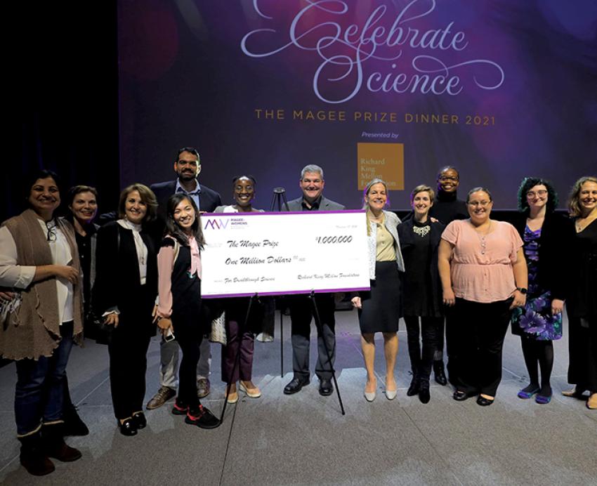 people on a stage holding a giant check