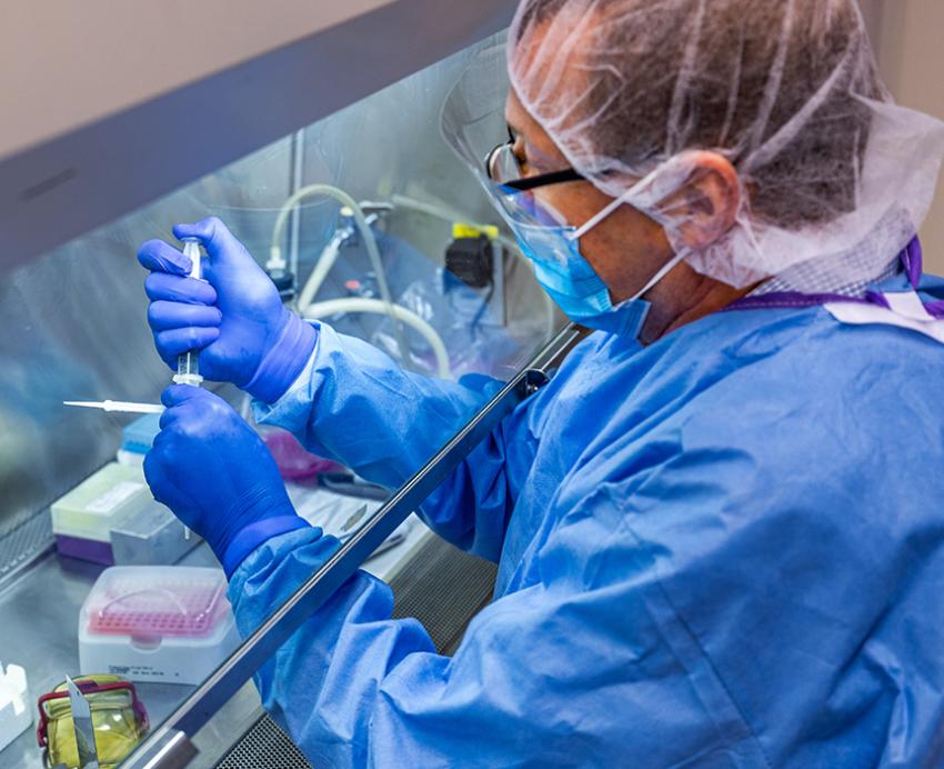 Man in mask filling up syringes in lab